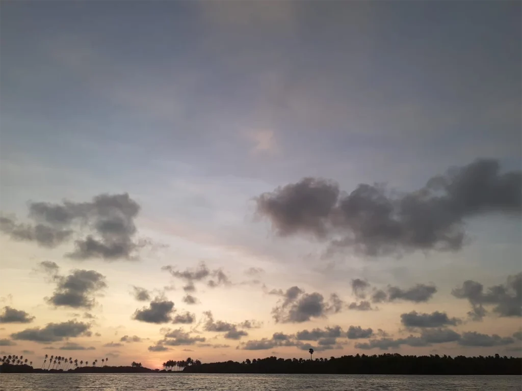 sun starting to set in sky. You can see the beach near coconut trees. lovely view